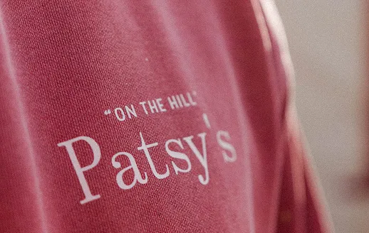 Close-up of a red fabric with white text reading 'ON THE HILL Patsy's'.