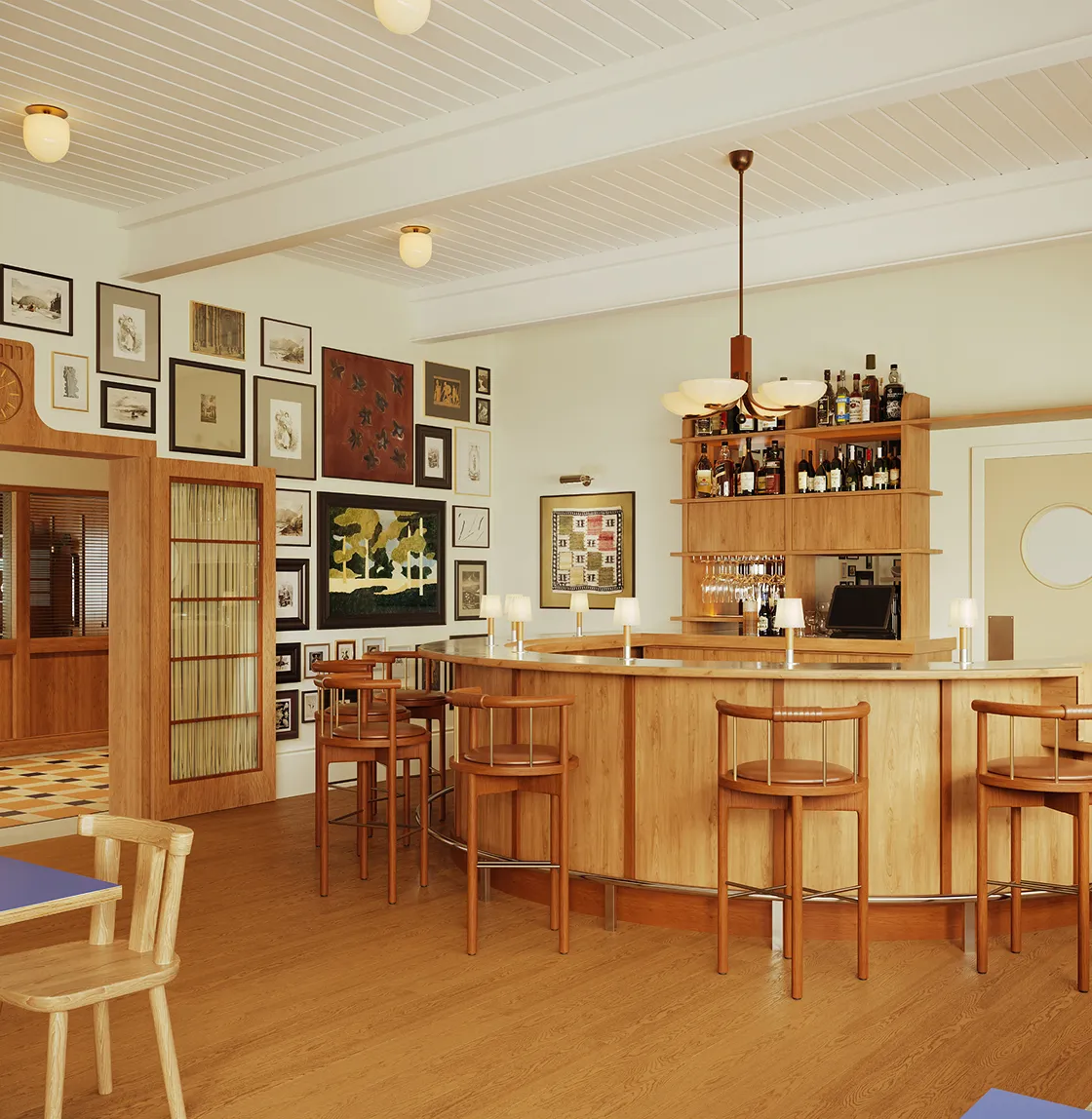 Cozy wooden bar area with stools, a variety of framed art on the wall, and a shelf with bottles and hanging glasses.