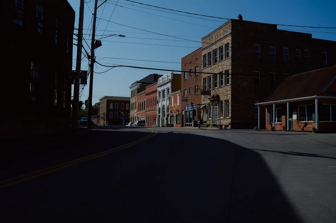 Quiet urban street with historic brick and stone buildings under a clear blue sky.