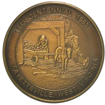 Commemorative medal depicting a miner with a cart pulled by a horse inside a mine, encircled by text reading '1883 Centennial 1983 Fayetteville, West Virginia'.