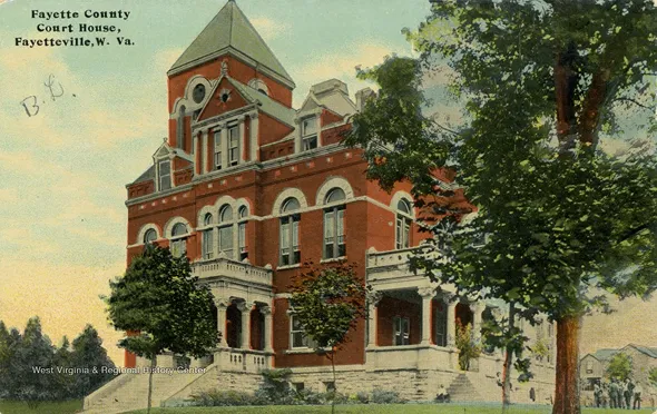 Historic Fayette County Court House in Fayetteville, West Virginia, a red brick building with arched windows and a central tower, surrounded by trees.