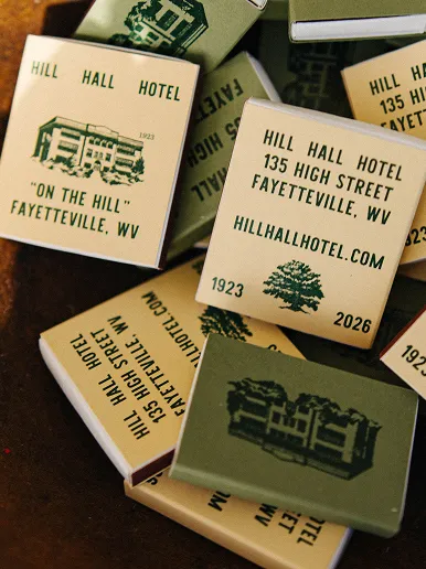 Close-up of Hill Hall Hotel matchboxes featuring hotel name, address, website, and illustrations of the building and a tree.