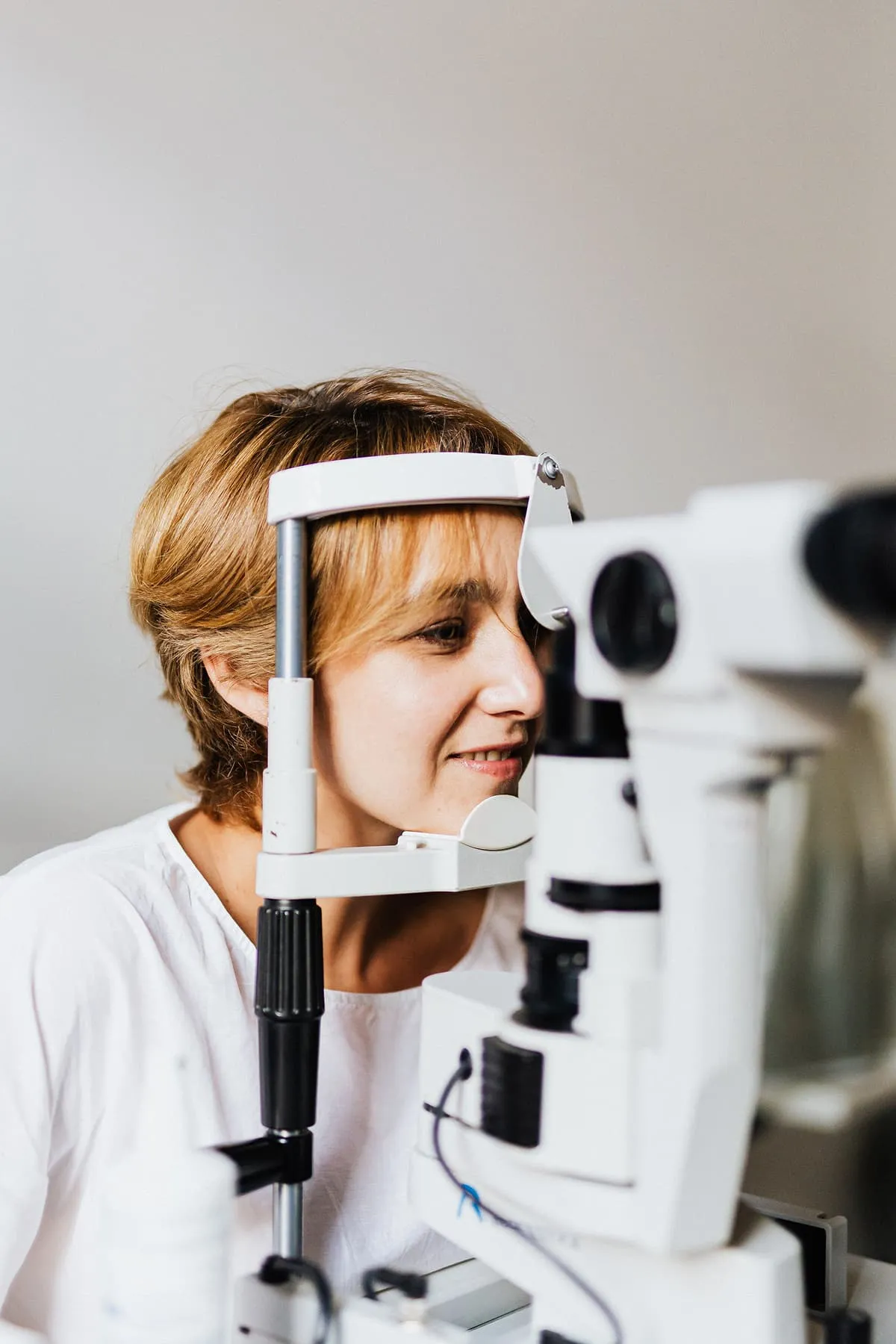 Woman undergoing an eye examination using a slit lamp in an ophthalmology clinic.