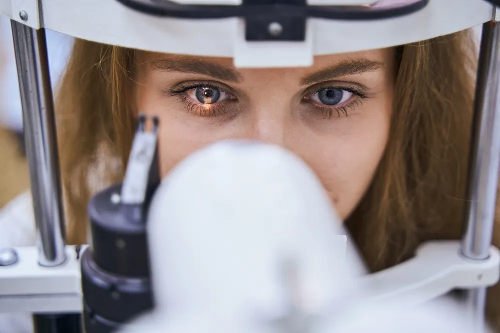 Close-up of a young woman undergoing an eye exam using a slit lamp microscope.