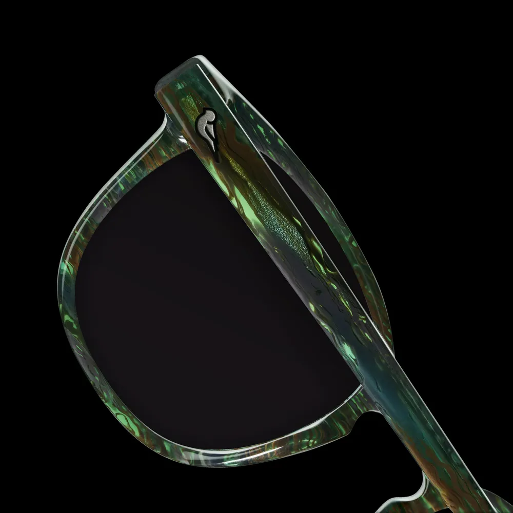 Close-up of sunglasses with a green and brown marbled frame and a dark lens on a black background.