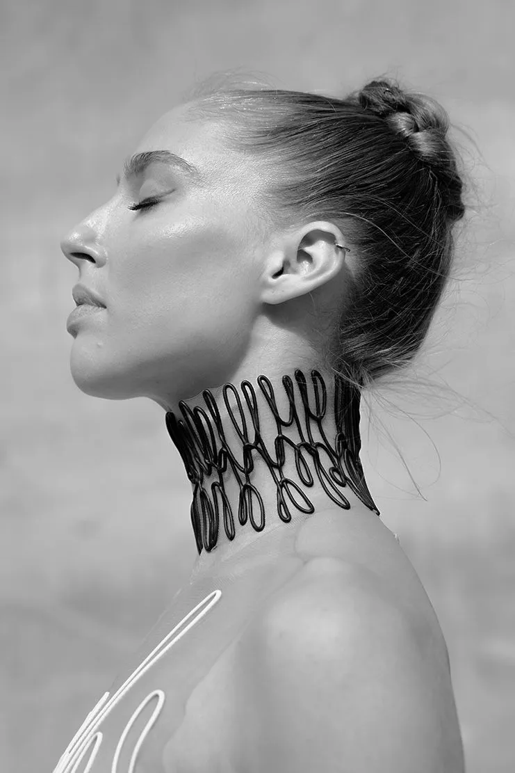 Woman with eyes closed, wearing a beaded choker, outdoors