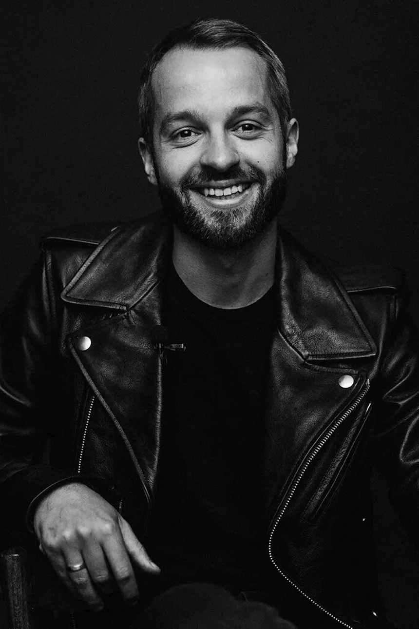Man with a beard smiling, wearing a leather jacket