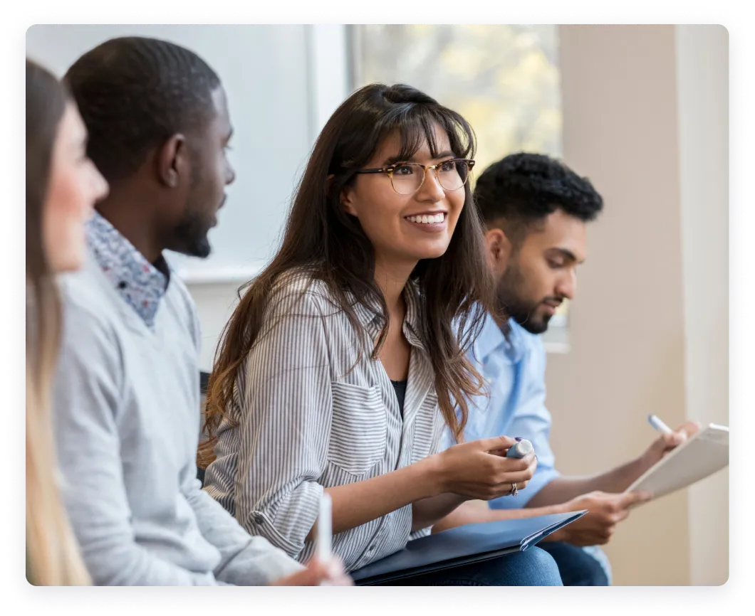 Group of individuals engaged in a discussion, with a smiling woman in the foreground.