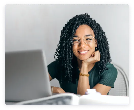 Joyful woman with glasses working at a laptop.