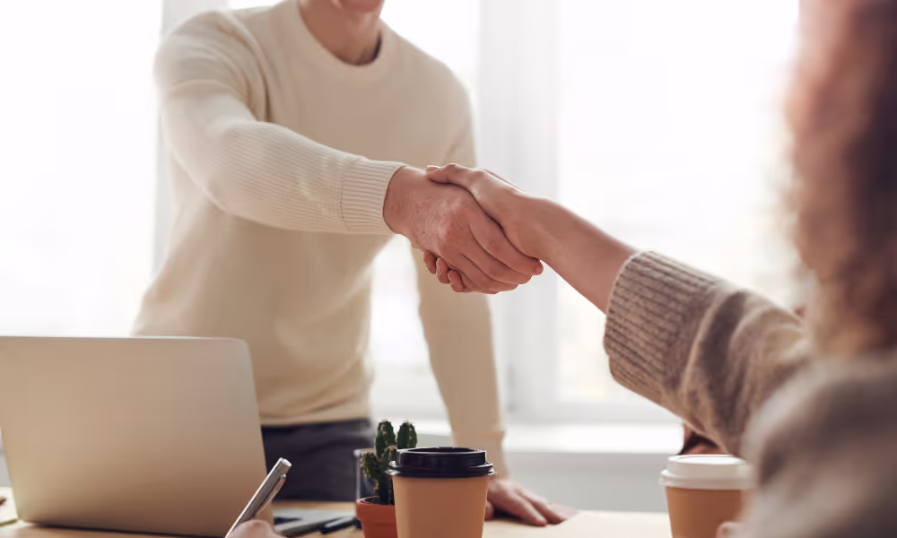Man and woman shaking hands, presumably during an interview.