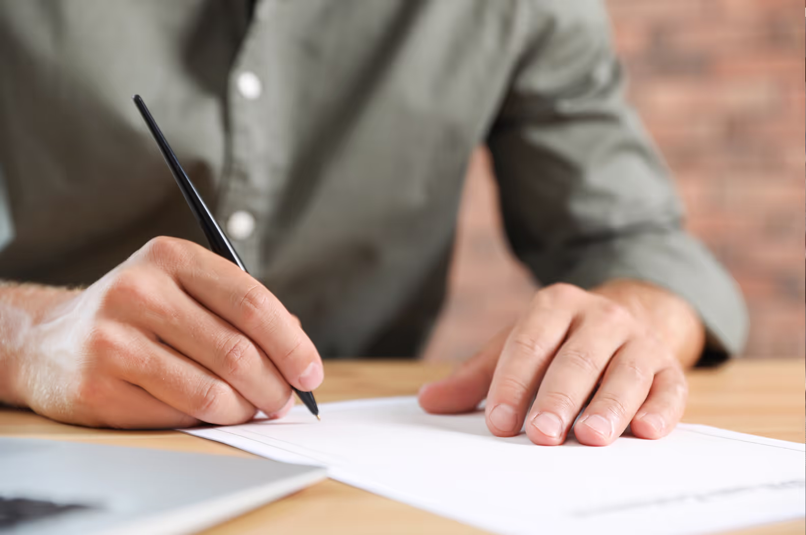 Someone filling out a form on a desk.
