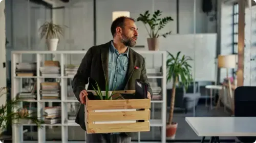 A person walking into their office with their belongings looking confused.