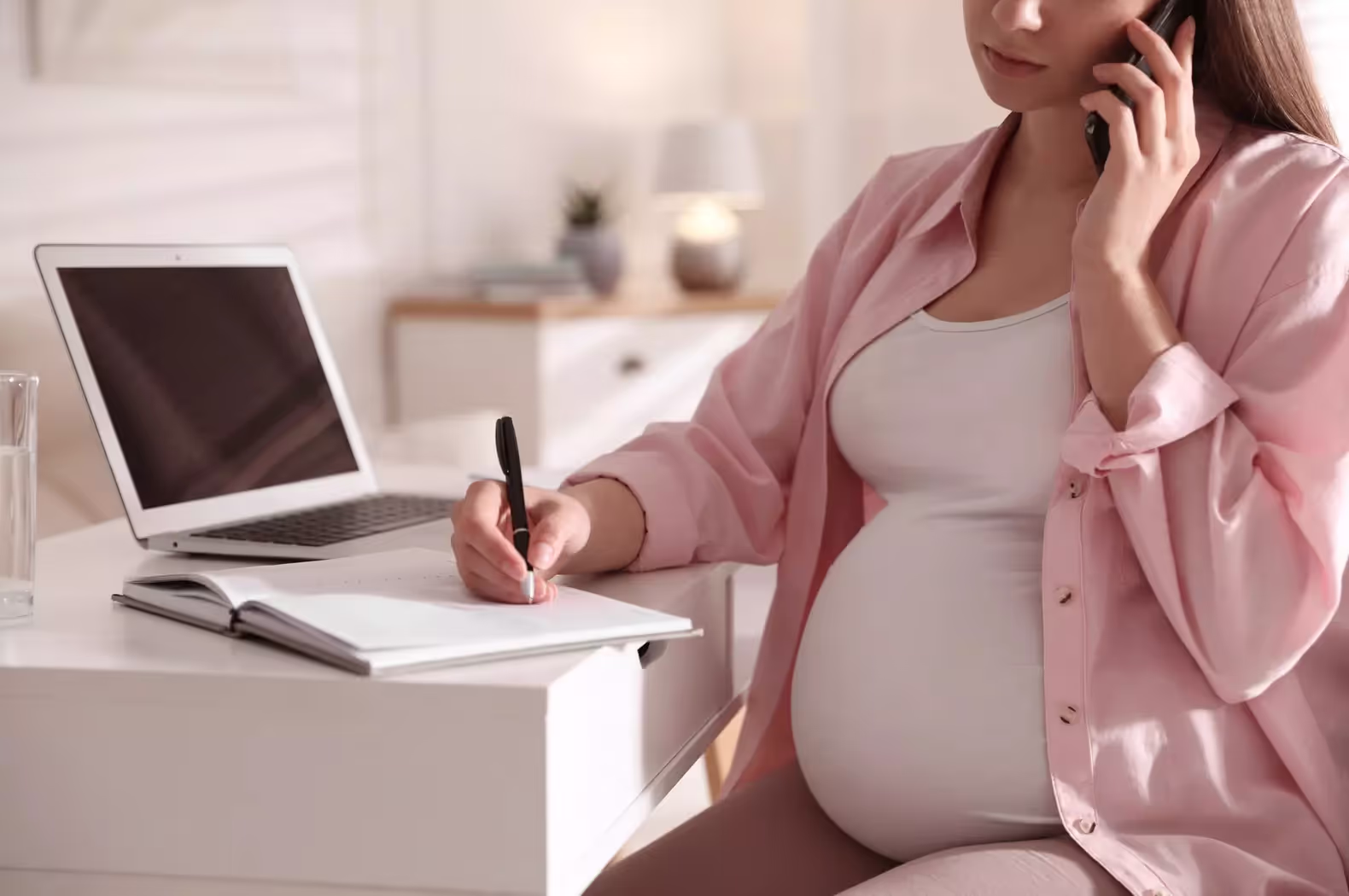 Pregnant person working from their desk.