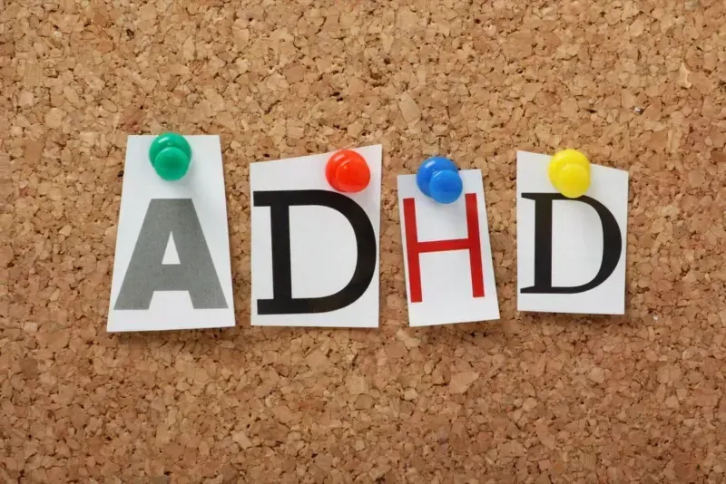 Letters spelling ADHD pinned to corkboard.