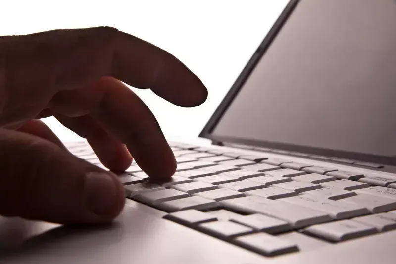 Close up of fingers typing on laptop.