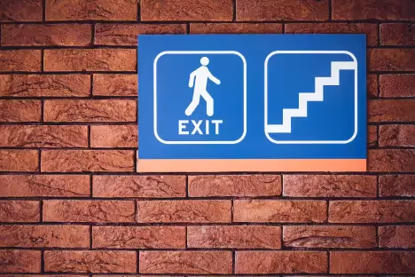 Blue exit sign with stairs symbol on brick wall. 