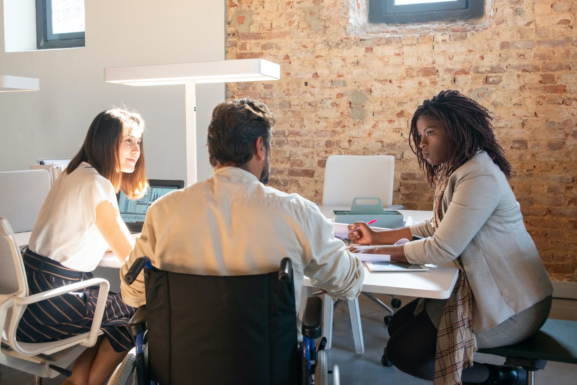 People gathered at a desk having a meeting.