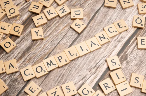 Lettered game pieces spelling out compliance