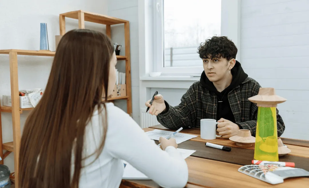 Two people talking over a desk.