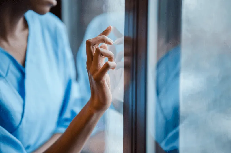 Medical professional pressing fingers against a glass window.