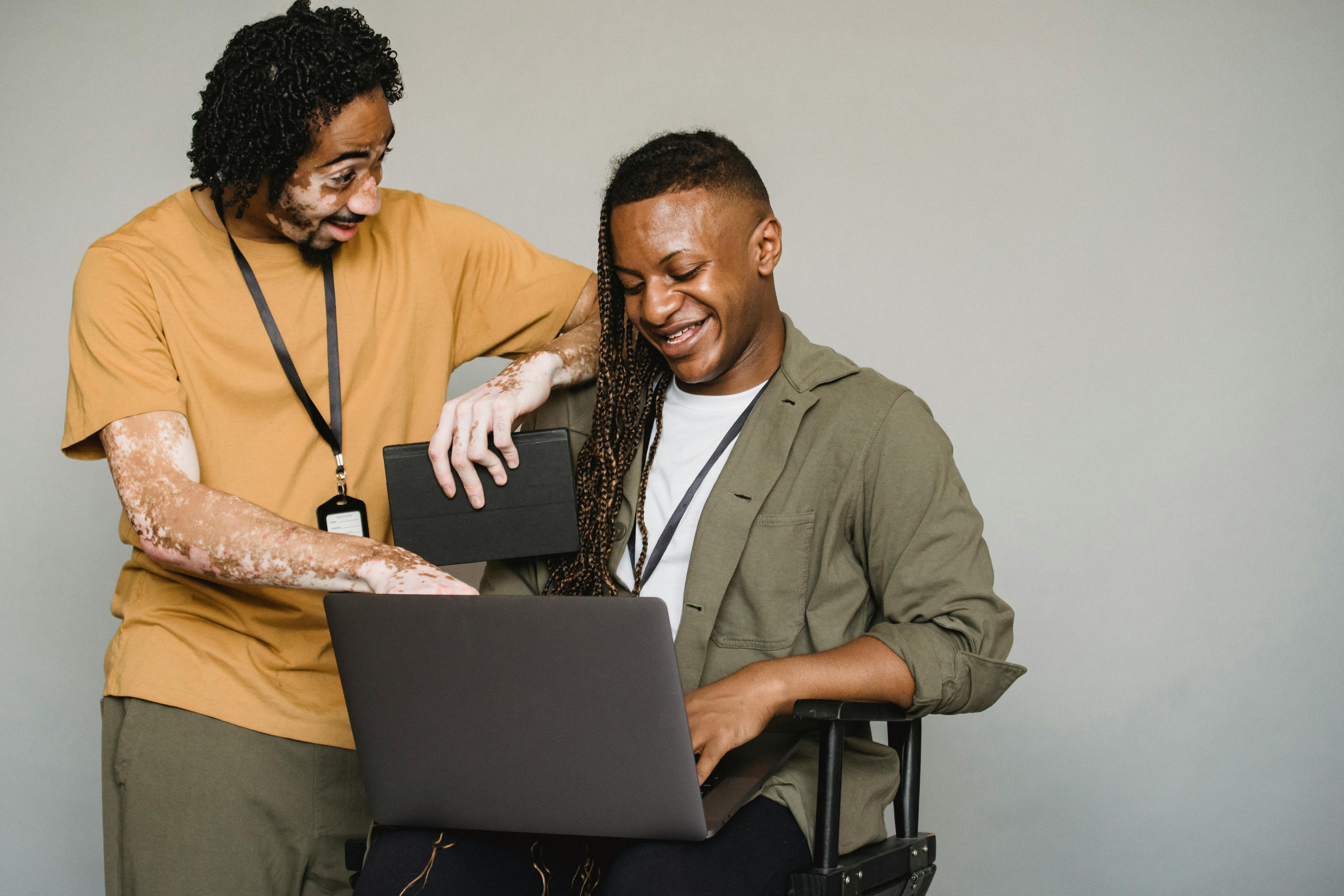 Cheerful coworkers look at laptop screen together.