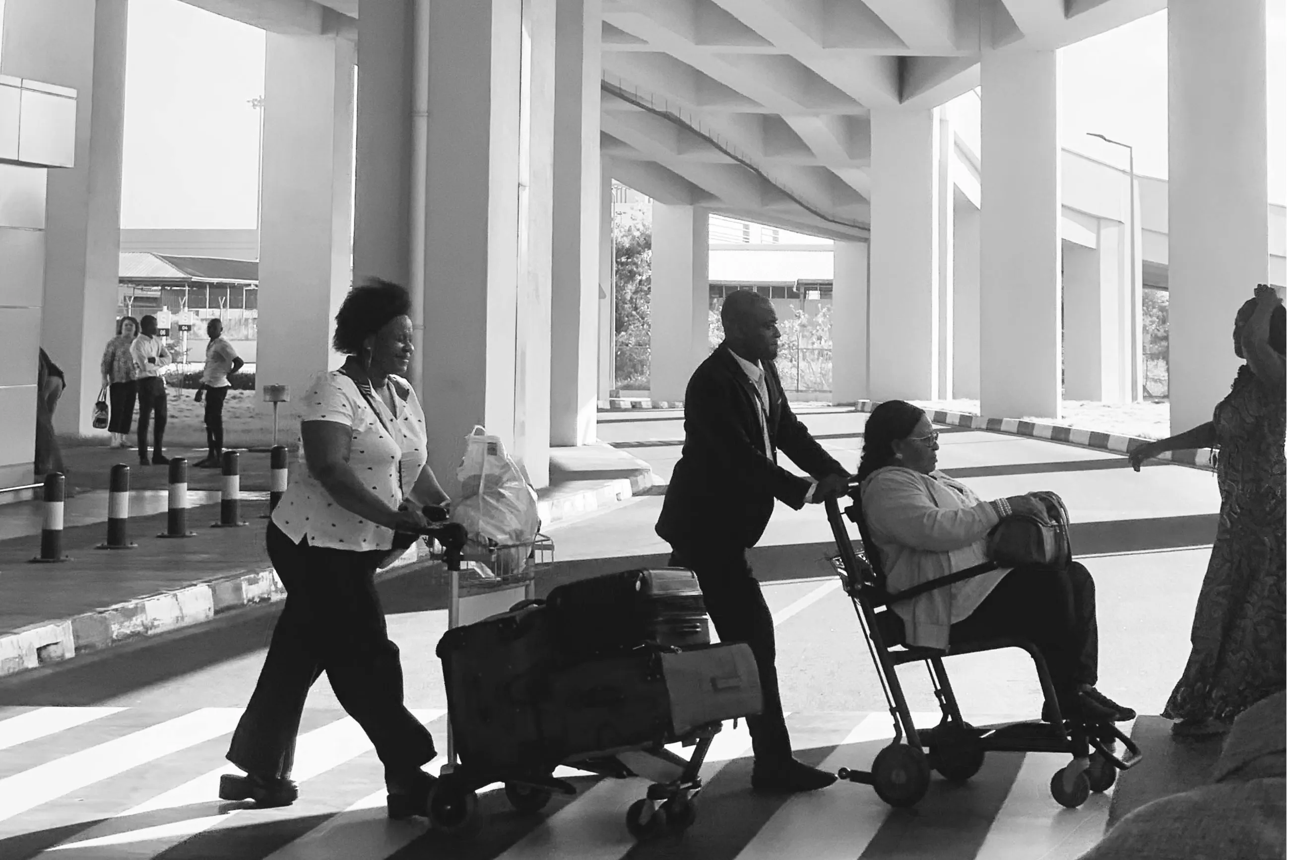 A group of people crossing the street with a wheelchair traveler. 