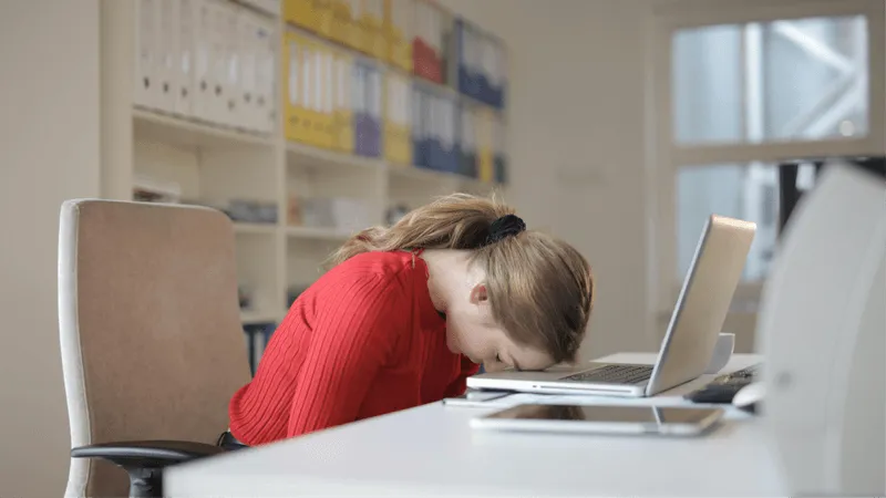 A person face down on their desk.