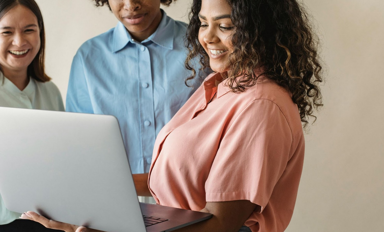 Three people looking at a laptop.