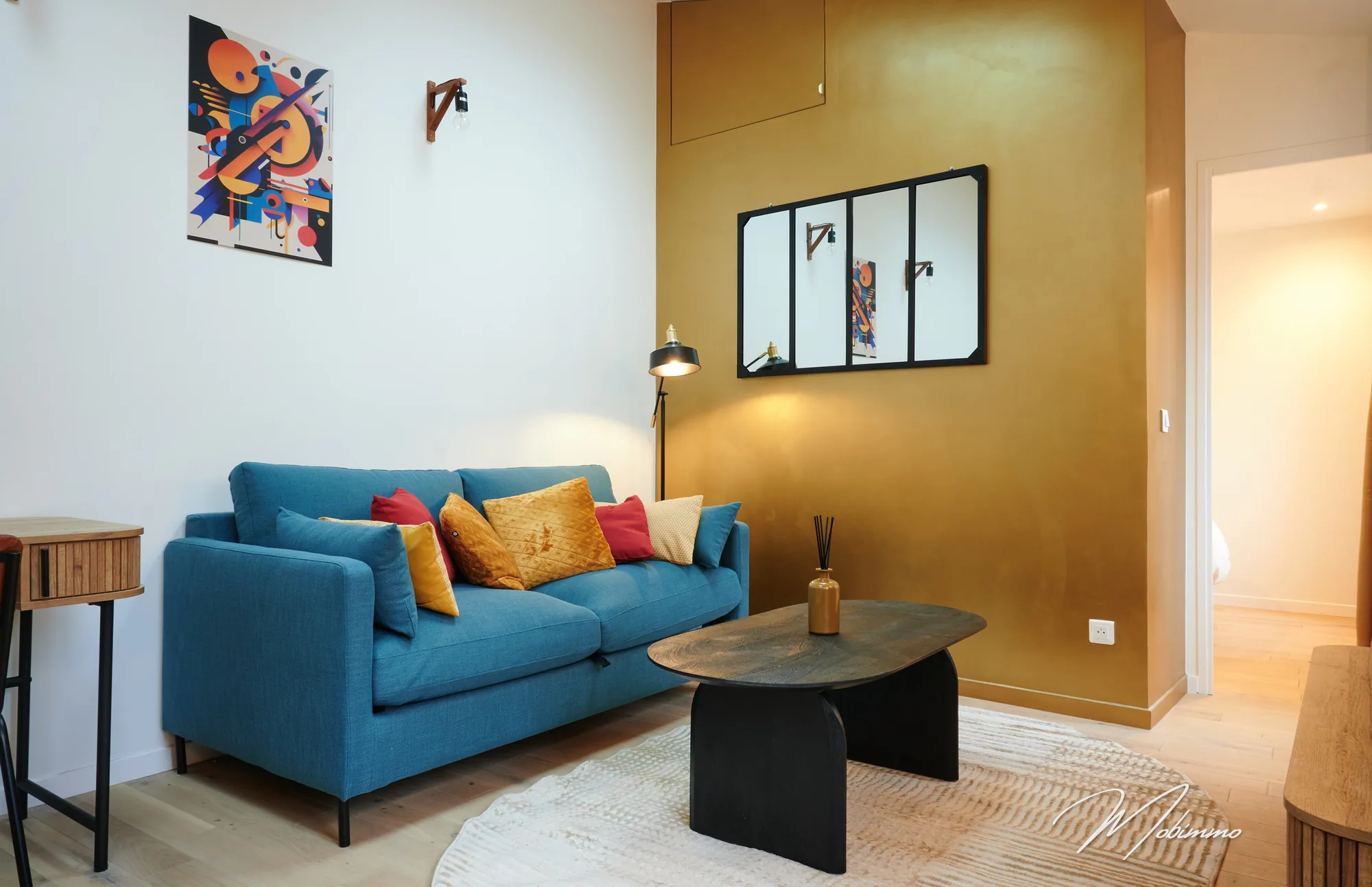 Séjour du T2 Kandinsky à Montmartre, canapé bleu et mur doré, meublé par Mobimmo