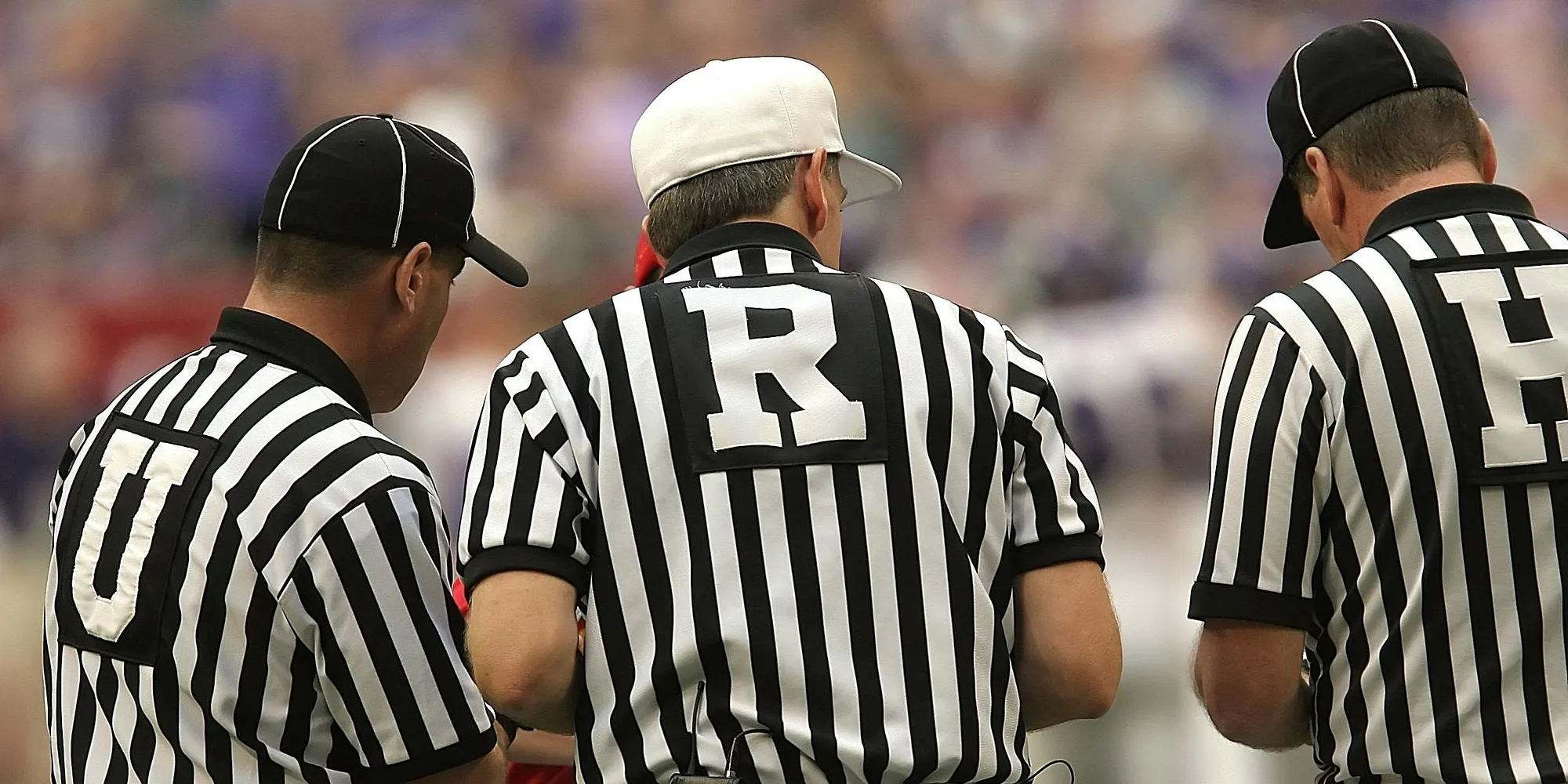 Referees in striped shirts discussing a call during a game.
