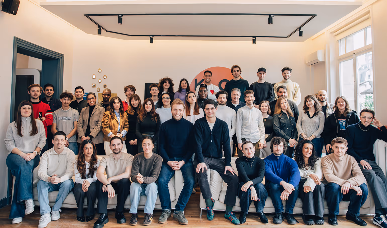 Equipe de Klox, 41 personnes posant ensemble dans une salle lumineuse avec un grand canapé et un mur clair en arrière-plan.