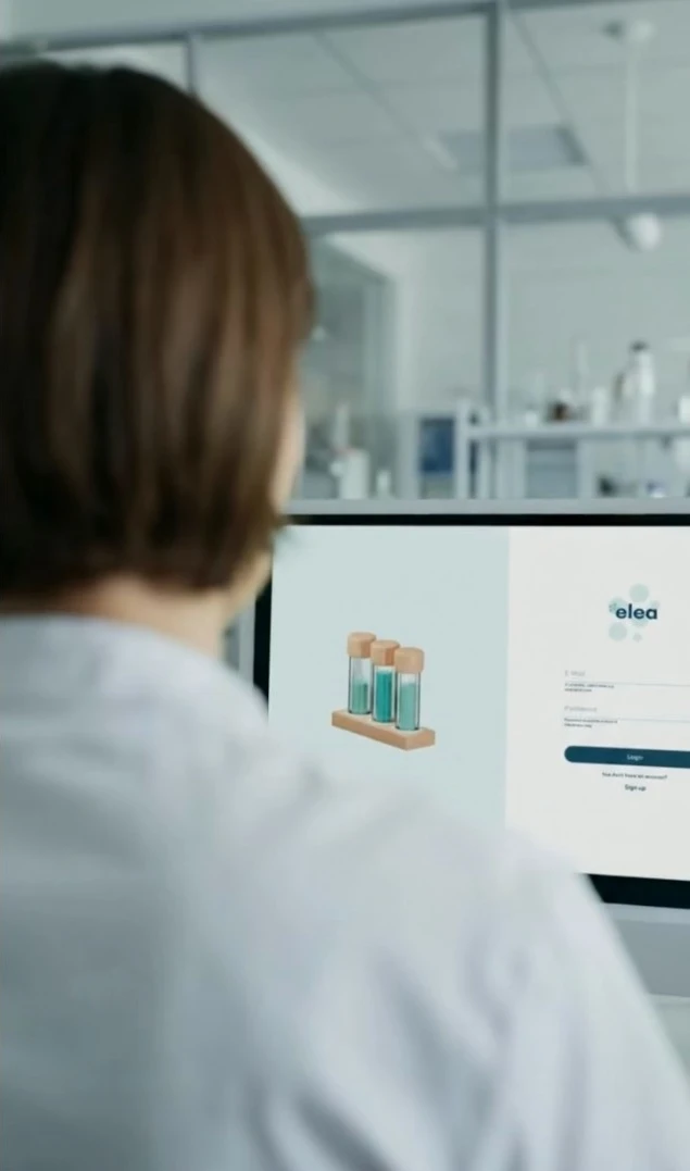 Person im Labor betrachtet Computerbildschirm mit Login-Seite und Grafik von Reagenzgläsern.