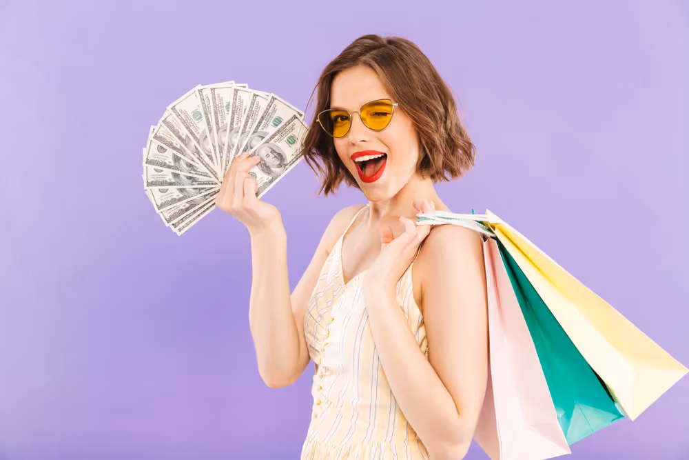 Smiling woman in white shirt holding up three credit cards and making an OK hand gesture.