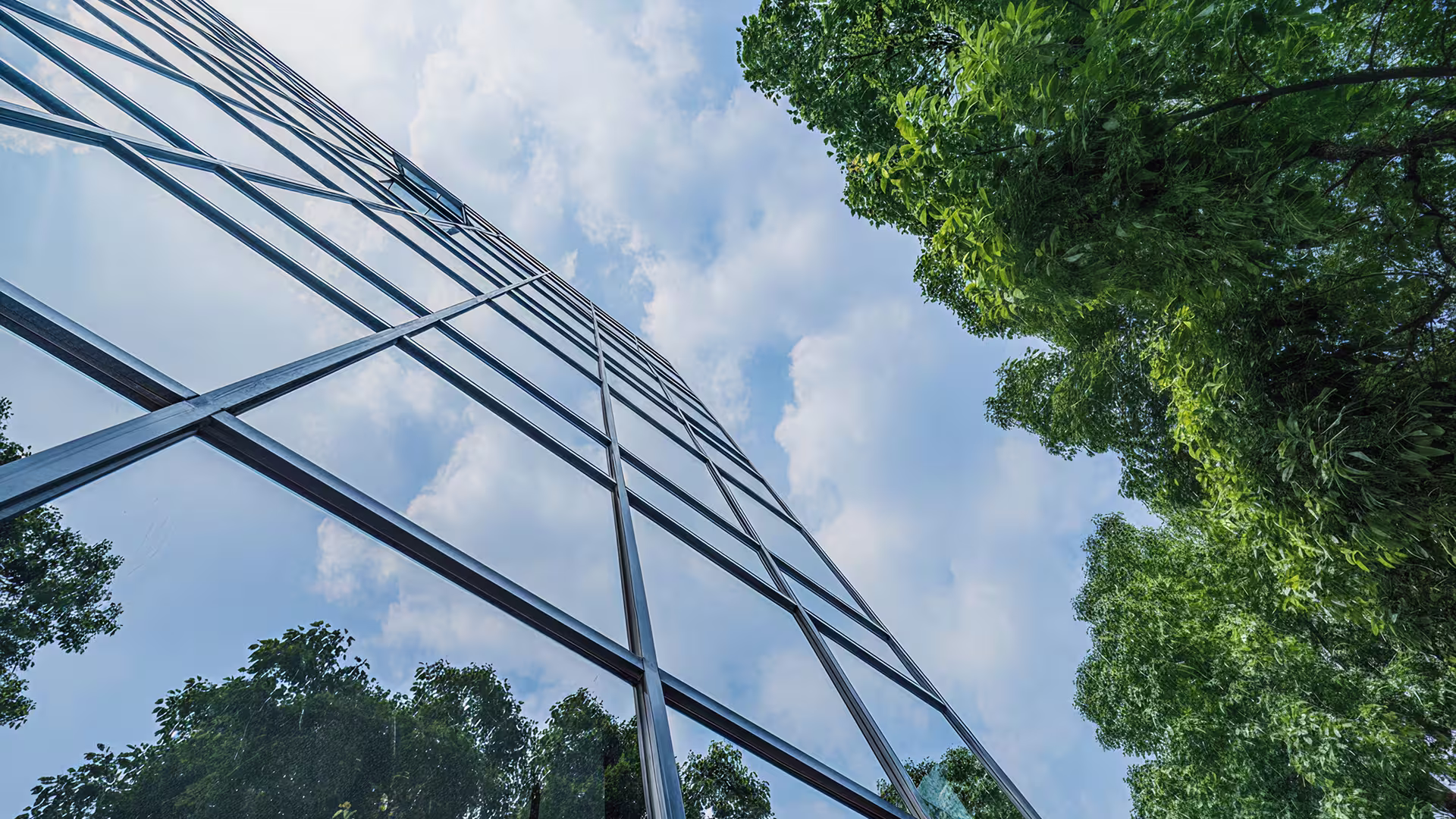 Immeuble en verre avec reflet des arbres environnants – architecture durable, HQE et intégration paysagère des bâtiments