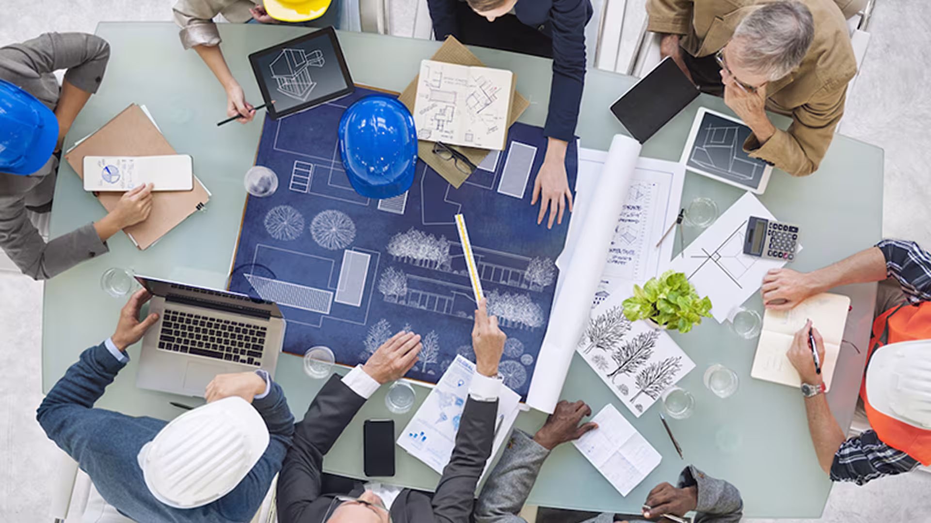 Top view of a team of architects meeting around site plans — project management and project engineering
