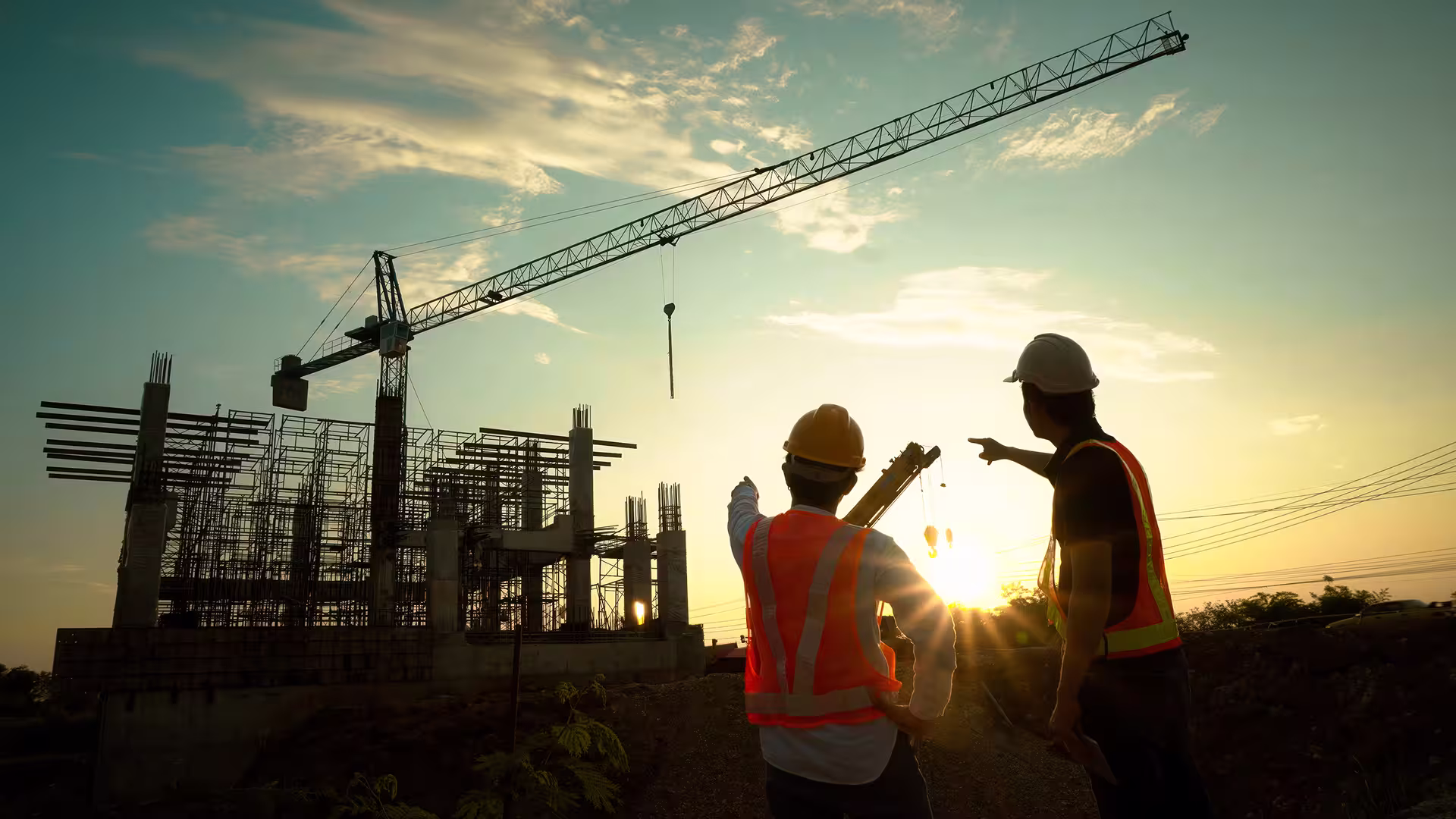 Workers and crane on a construction site bathed in sunset light
