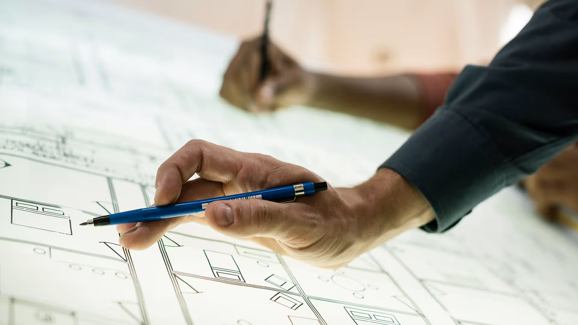 Mains posées sur des plans architecturaux déroulés, illustration pour Dispense de versement de précompte professionnel pour travaux immobiliers