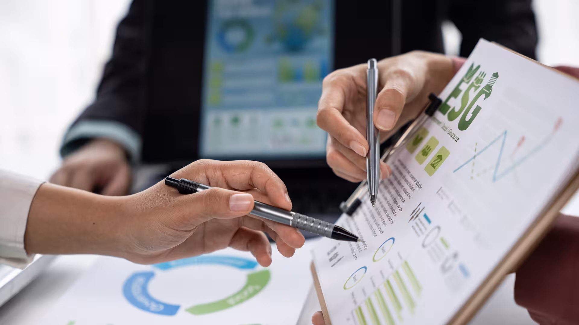 Mains pointant un rapport ESG avec graphiques, stylos posés autour, illustration pour Coordination et supervision d'assainissement