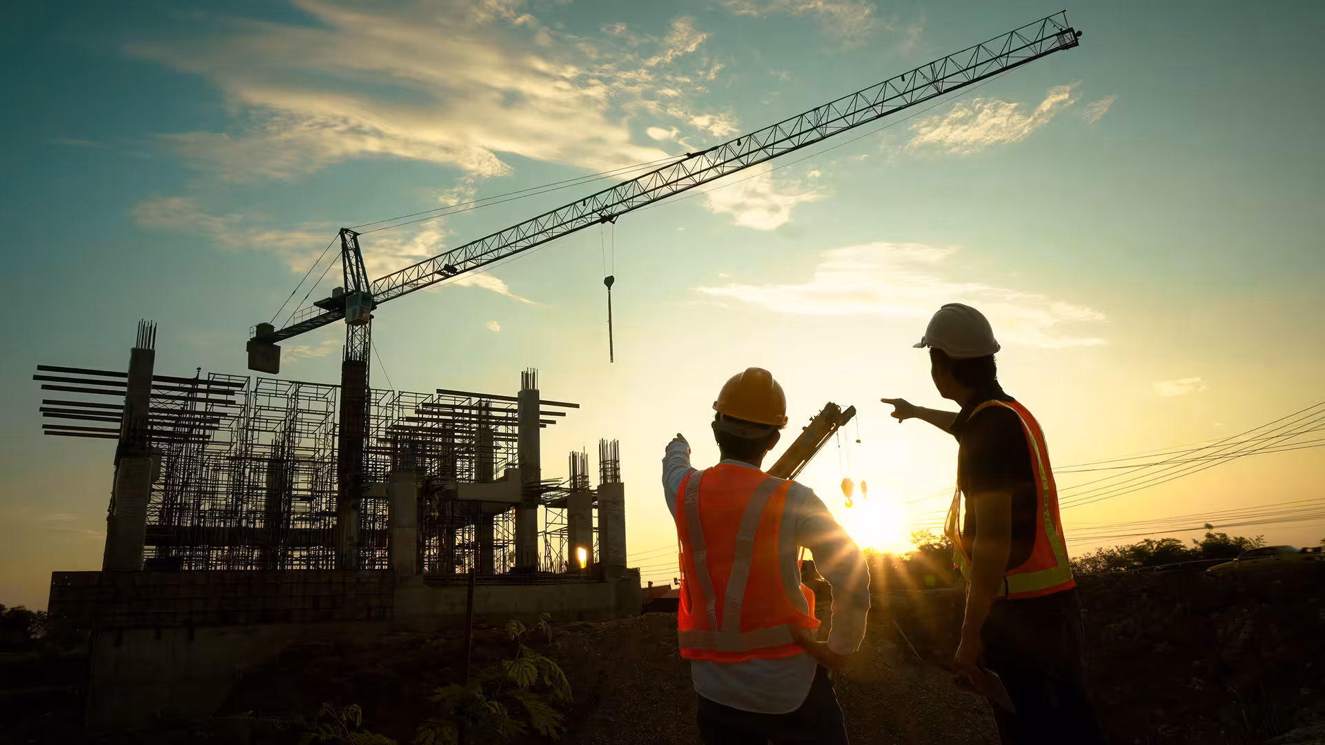 Workers and crane on a construction site bathed in sunset light