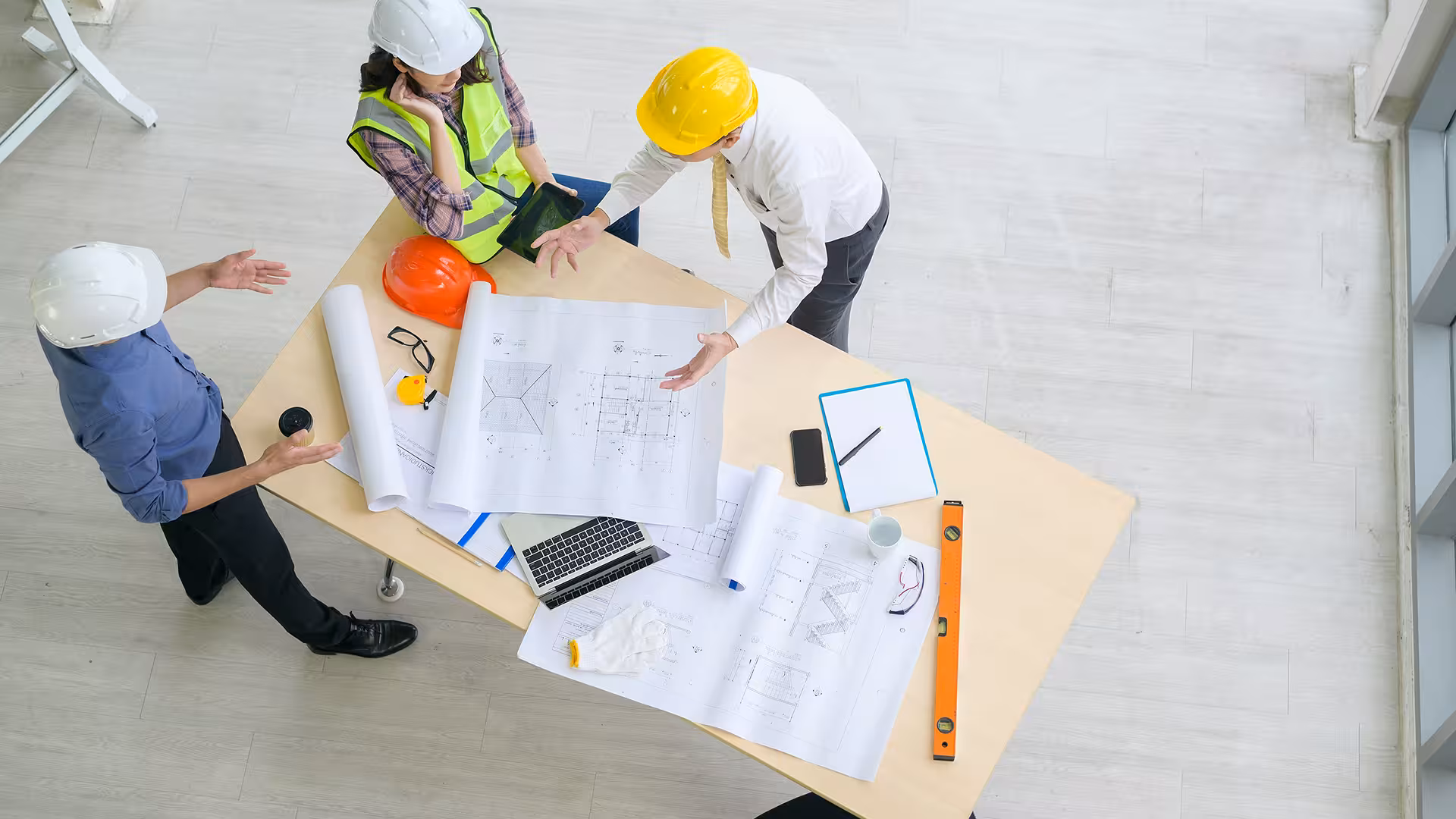 Top view of a team working on architectural plans, illustration for Outsourcing QSE coordinator
