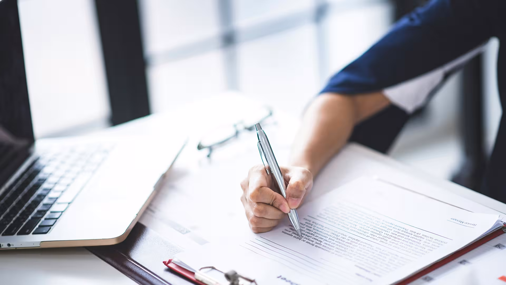 Main signant un document contractuel sur un bureau, illustration pour Étude environnementale