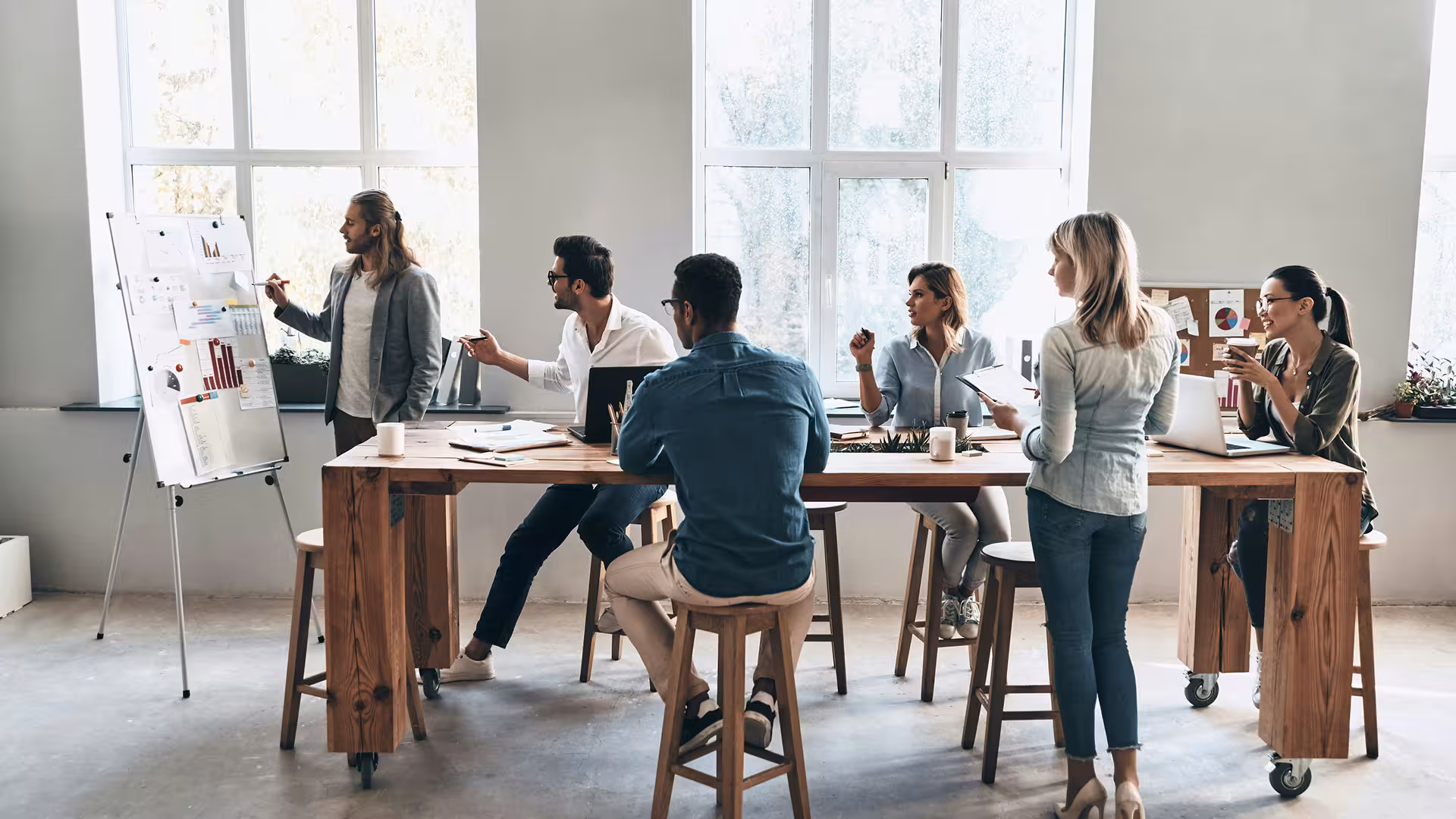 Équipe en séance de brainstorming devant un tableau dans un bureau lumineux
