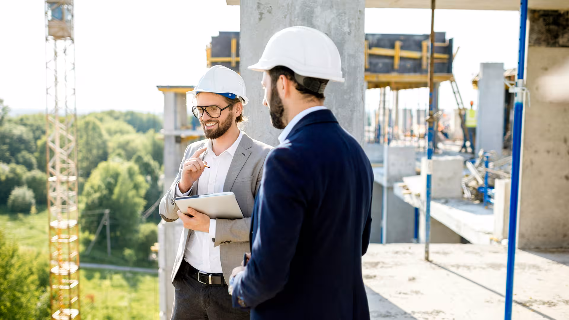 Managers casqués en discussion sur chantier autour d'une tablette, illustration pour Outsourcing coordinateur QSE