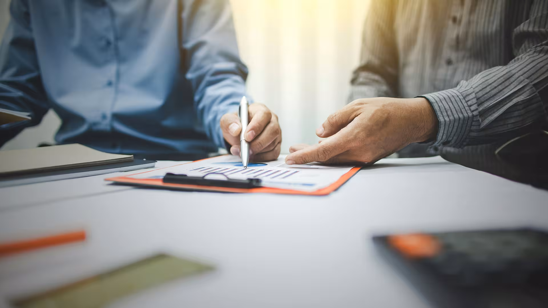 Deux personnes en train de revoir des documents dans un bureau, illustration pour Permis, autorisations & compliance