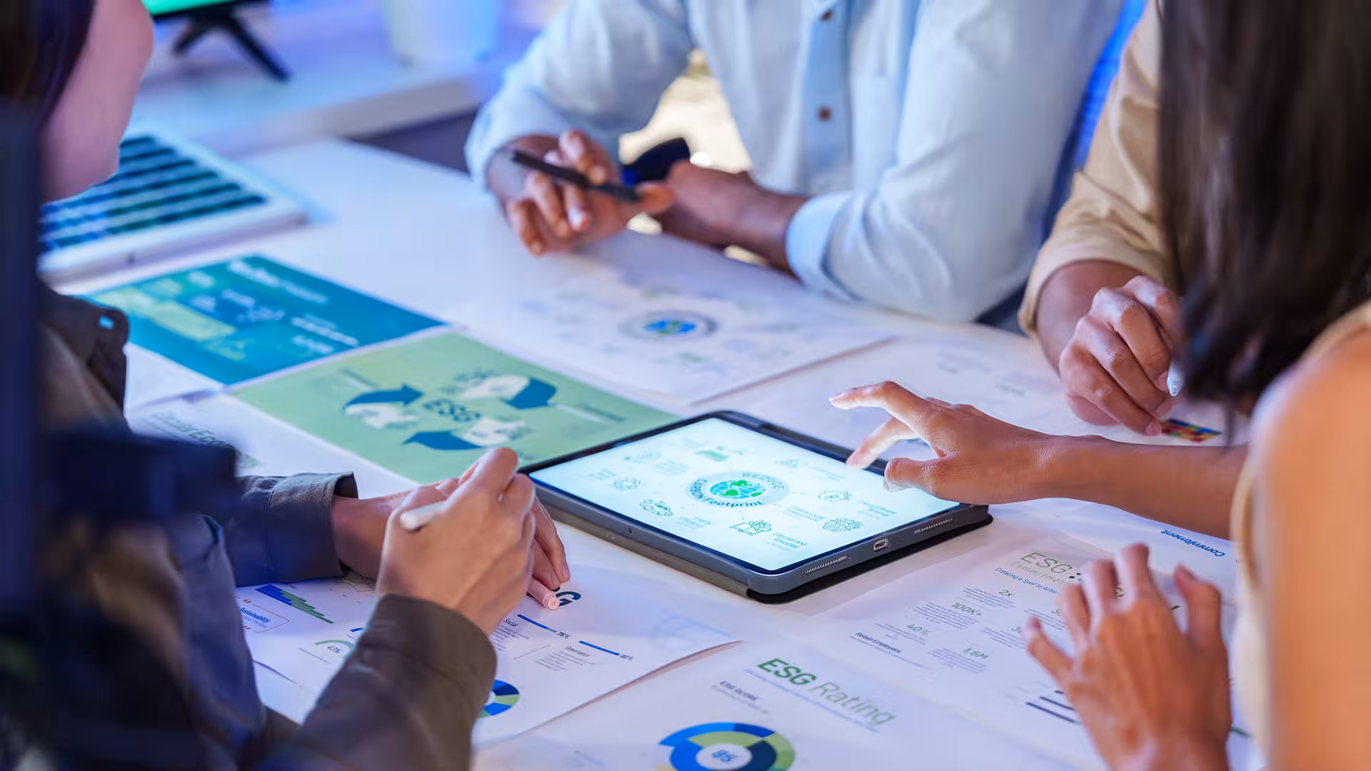 Équipe consultant des rapports ESG sur tablette lors d'une réunion, illustration pour Reporting, ESG et RSE