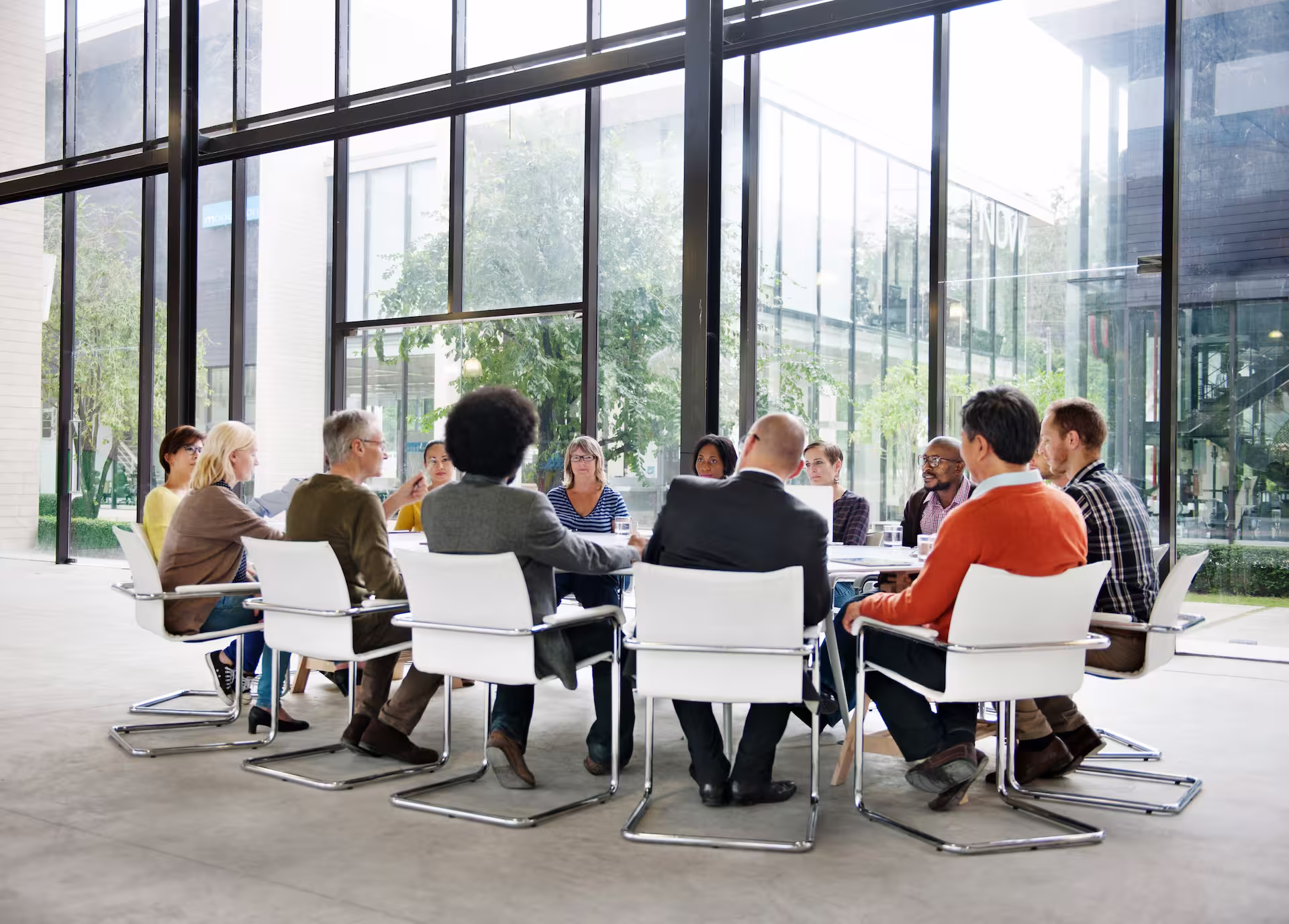 Groupe de personnes réunies autour d’une table dans une salle de réunion moderne et lumineuse, participant à une discussion