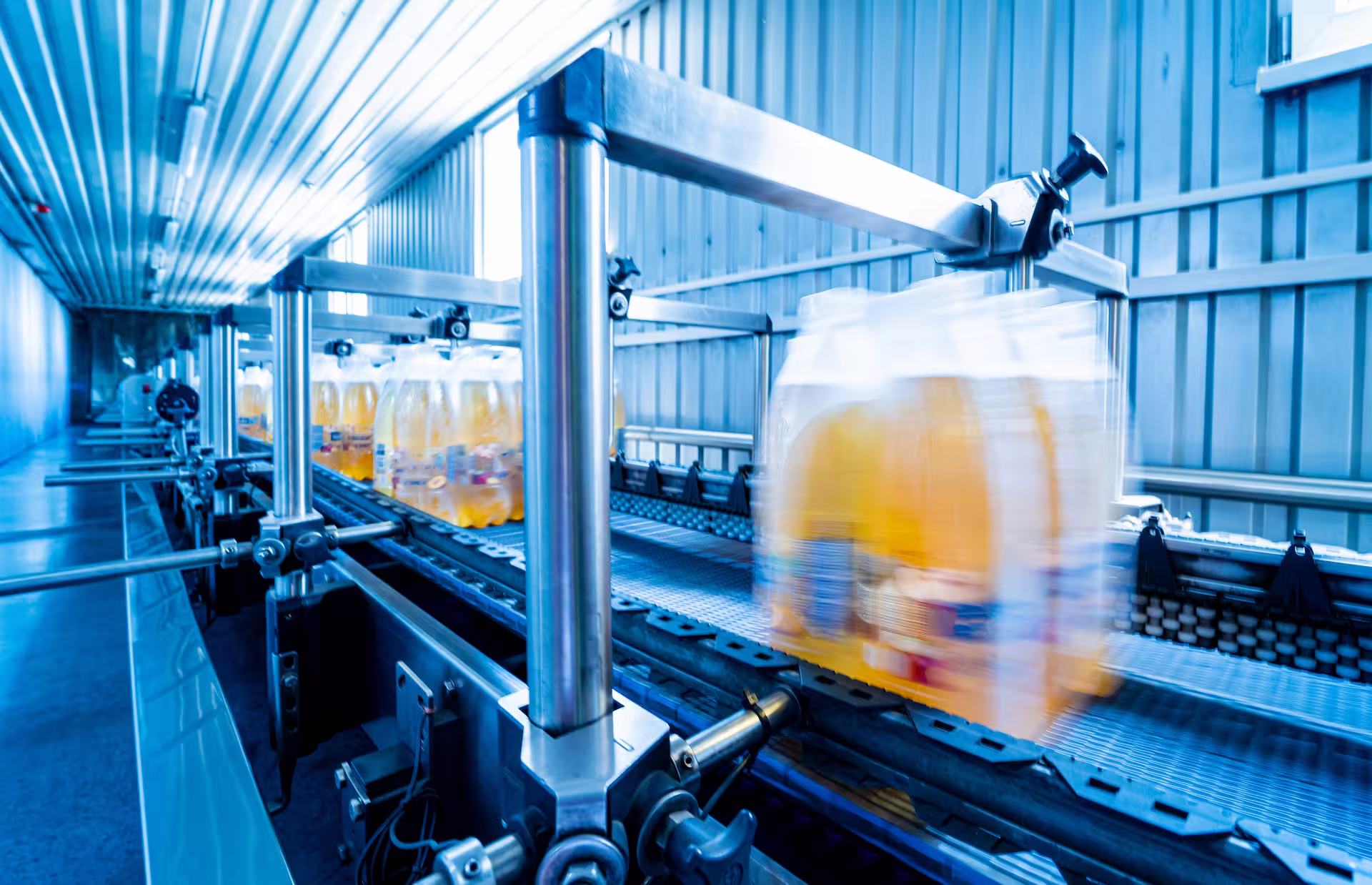 Packaged fruit juice bottles moving along an automated conveyor belt in a packaging plant.