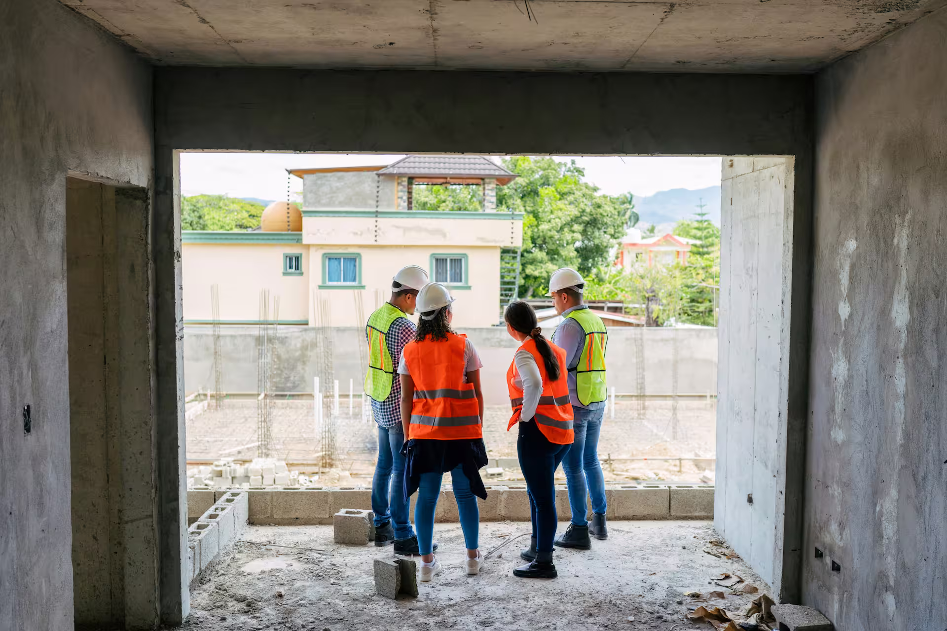 Quatre professionnels en réunion sur un chantier de construction dans un bâtiment en cours de réalisation.