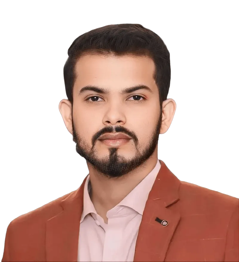 Portrait of a confident man with short dark hair and beard wearing a rust-colored blazer over a white shirt.