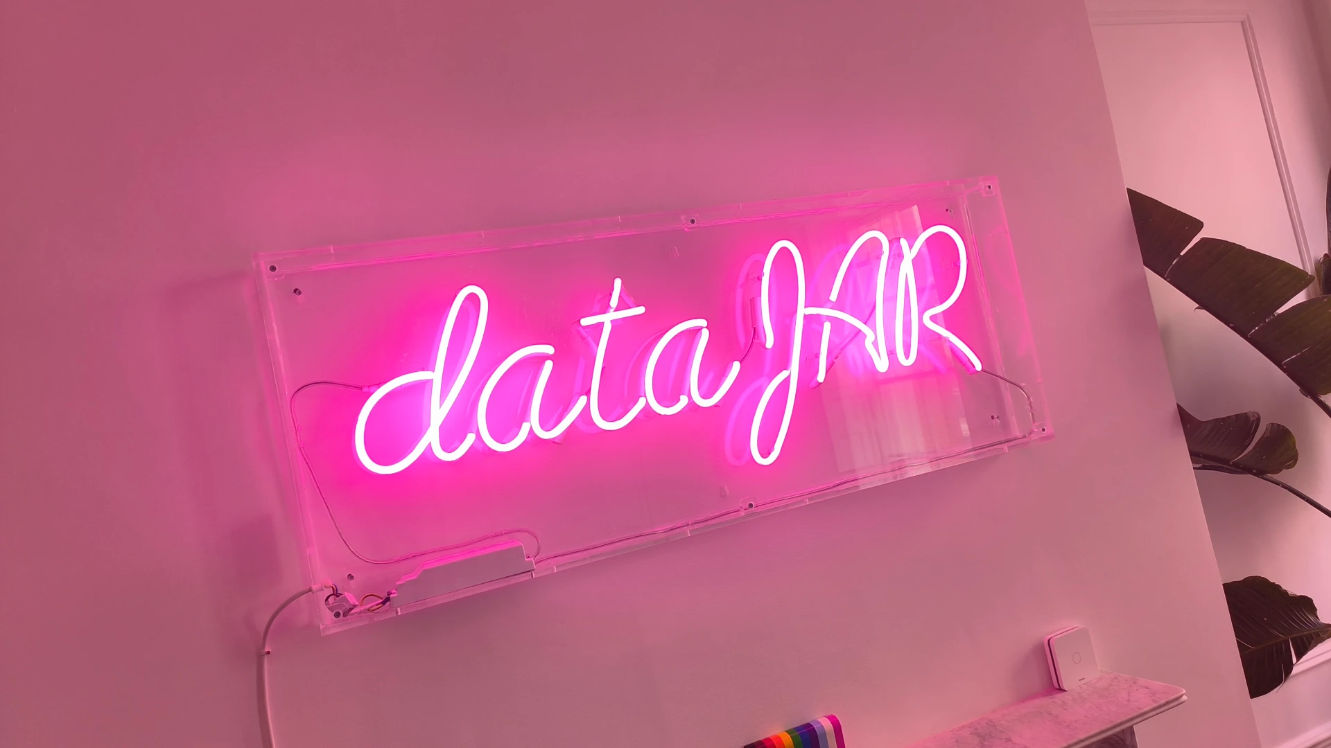 Pink neon DataHR sign on an office wall.